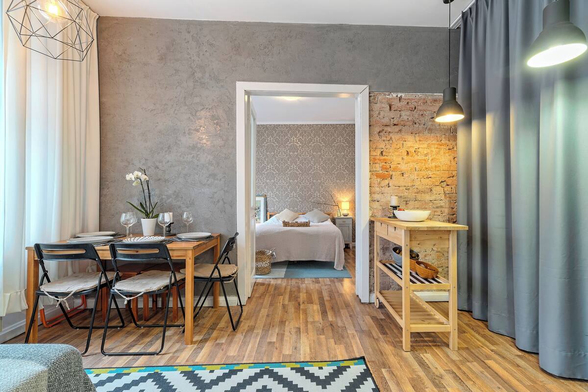 A modern room with a wooden dining table, chairs, a bed, and a small table with a bowl.