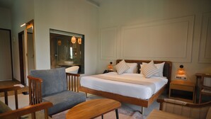 A bedroom with a bed, two bedside tables, a chair, a small table, and a mirror.