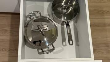 A drawer with two stainless steel pots and a pan.