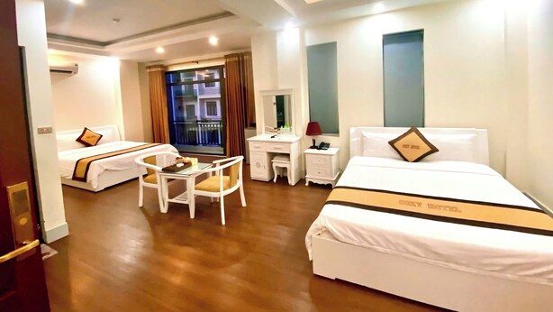Una habitación de hotel con dos camas, un escritorio, una silla y un ventanal con cortinas.