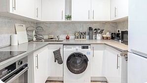 Une cuisine moderne avec des meubles blancs, un lave-linge encastré et un four à micro-ondes.