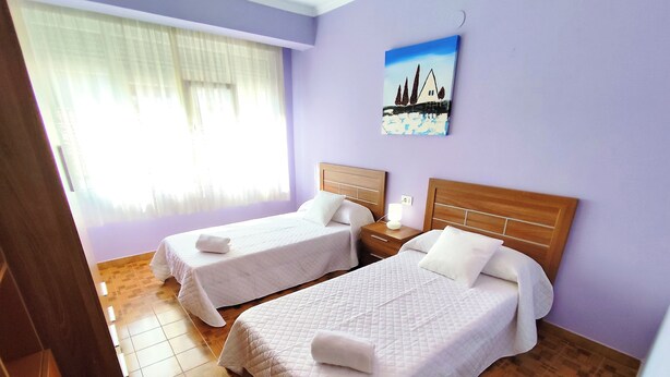 A hotel room with two beds, a painting on the wall, and a window with curtains. - Airtegal Litoral 49 (Cedeira)