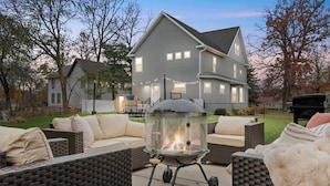A backyard with a fire pit, wicker furniture, and a house in the background. - Walk Downtown + Hot Tub + Sauna + Game Room + Pets (Wisconsin Dells)