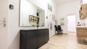 A modern hallway with a large mirror, a black cabinet, and a wooden shelf with plants. - Spacious 5BR Apt Close to Augarten (Vienna)