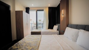 Habitación de hotel con dos camas, un armario, un balcón con vistas y una lámpara moderna.