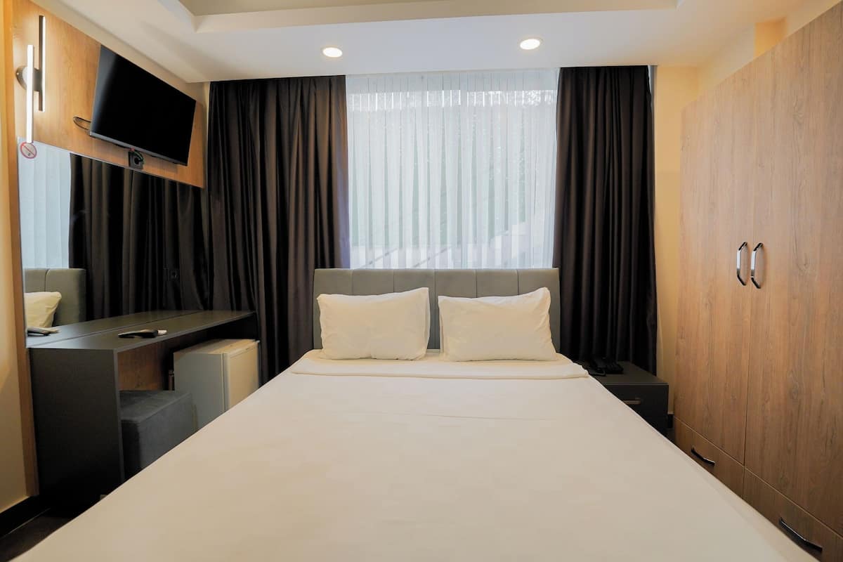 A hotel room with a bed, a desk, a TV, and a wardrobe.