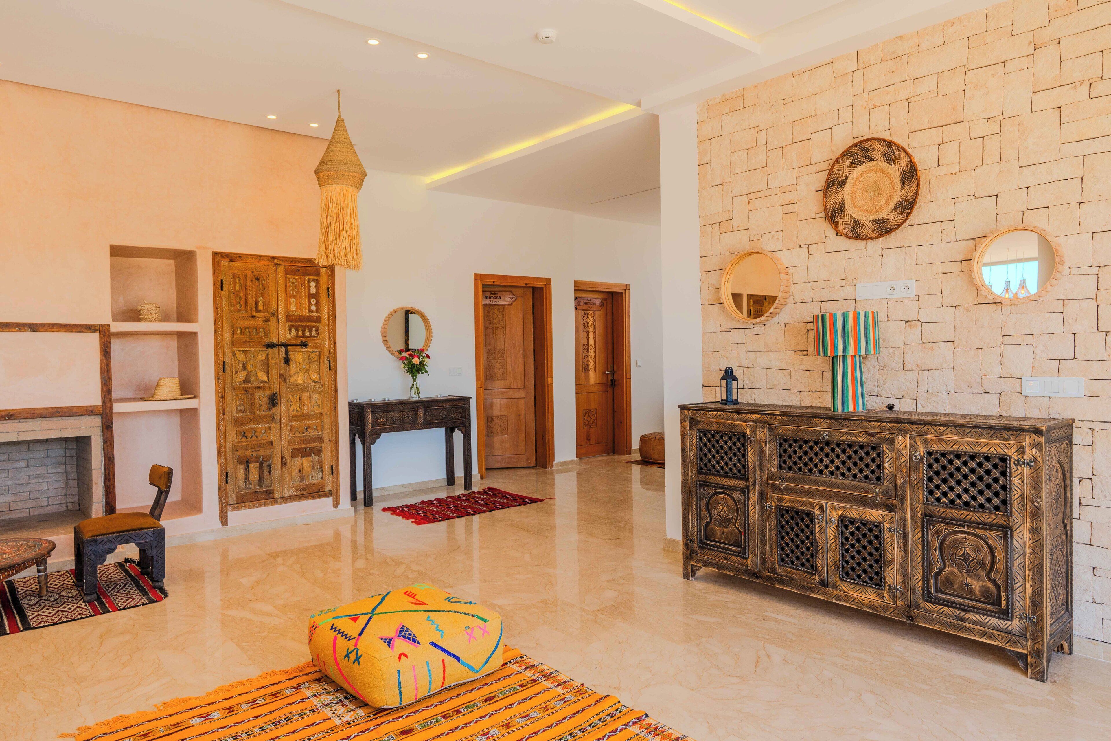 A spacious lobby with a wooden cabinet, a hanging light fixture, and a decorative mirror on the wall.