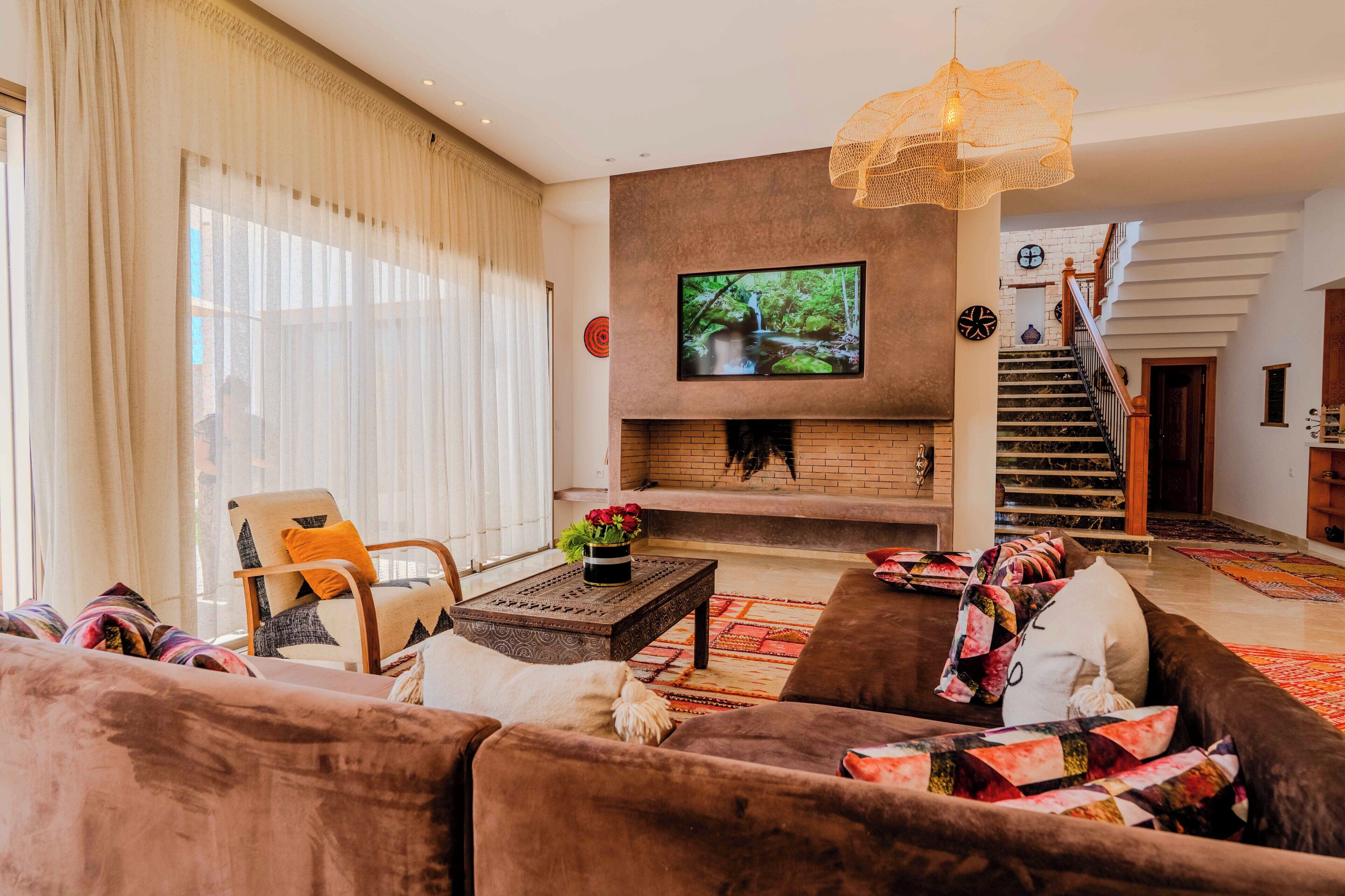 Een woonkamer met een open haard, een televisie en een trap naar een verdieping.