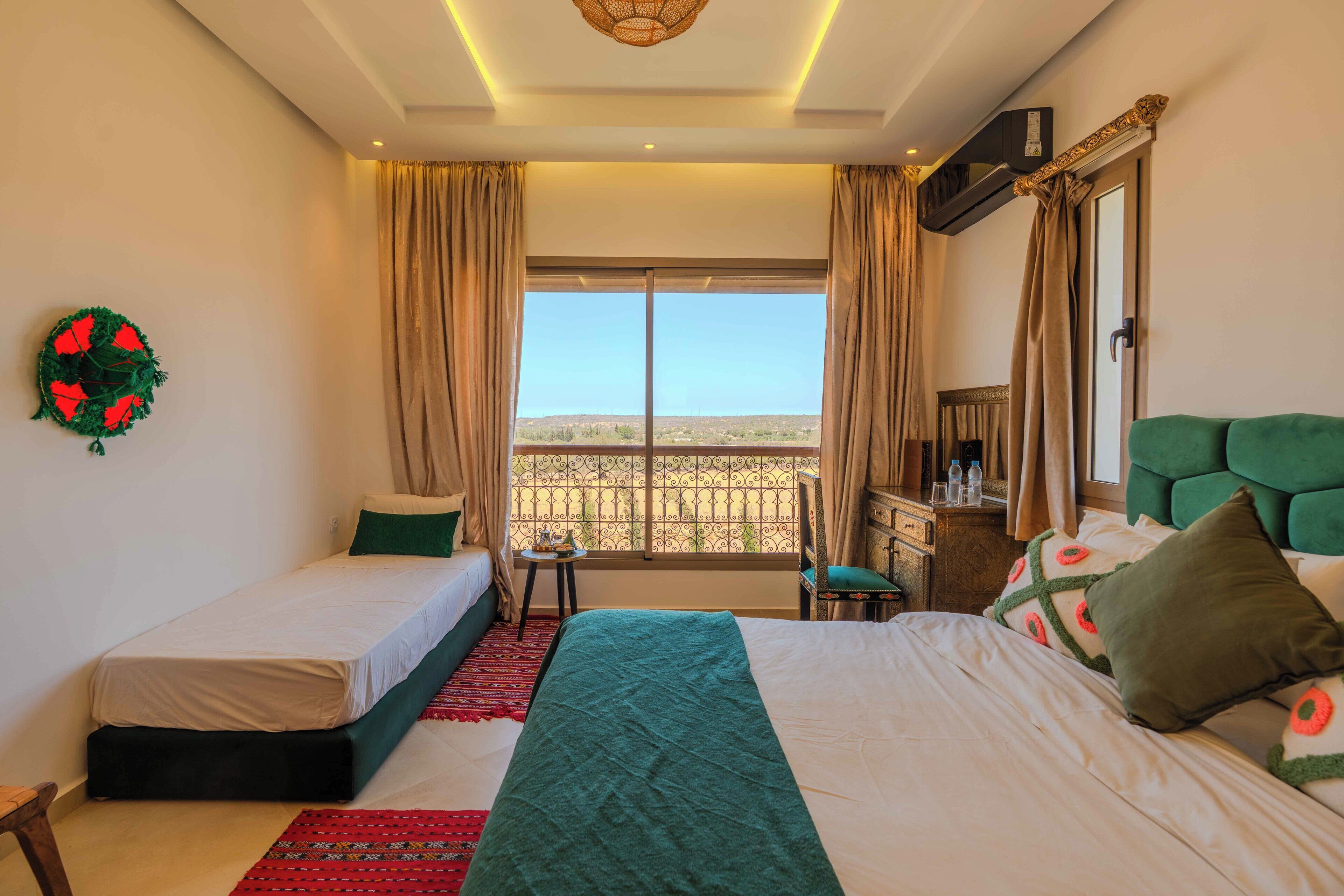 Una habitación de hotel con dos camas, un balcón con vistas y una guirnalda decorativa verde en la pared.