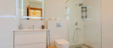 A modern bathroom with a glass-enclosed shower, a white vanity with a mirror, and a marble floor.