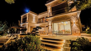 Una casa moderna de dos pisos con fachada de piedra, ventanas amplias y un patio exterior bien iluminado.