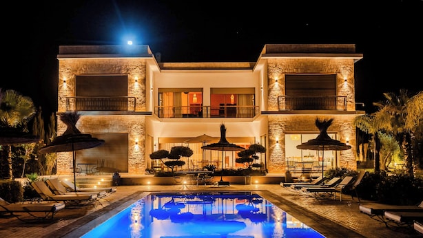 Una casa moderna de dos pisos con piscina, mobiliario exterior y un patio bien iluminado.