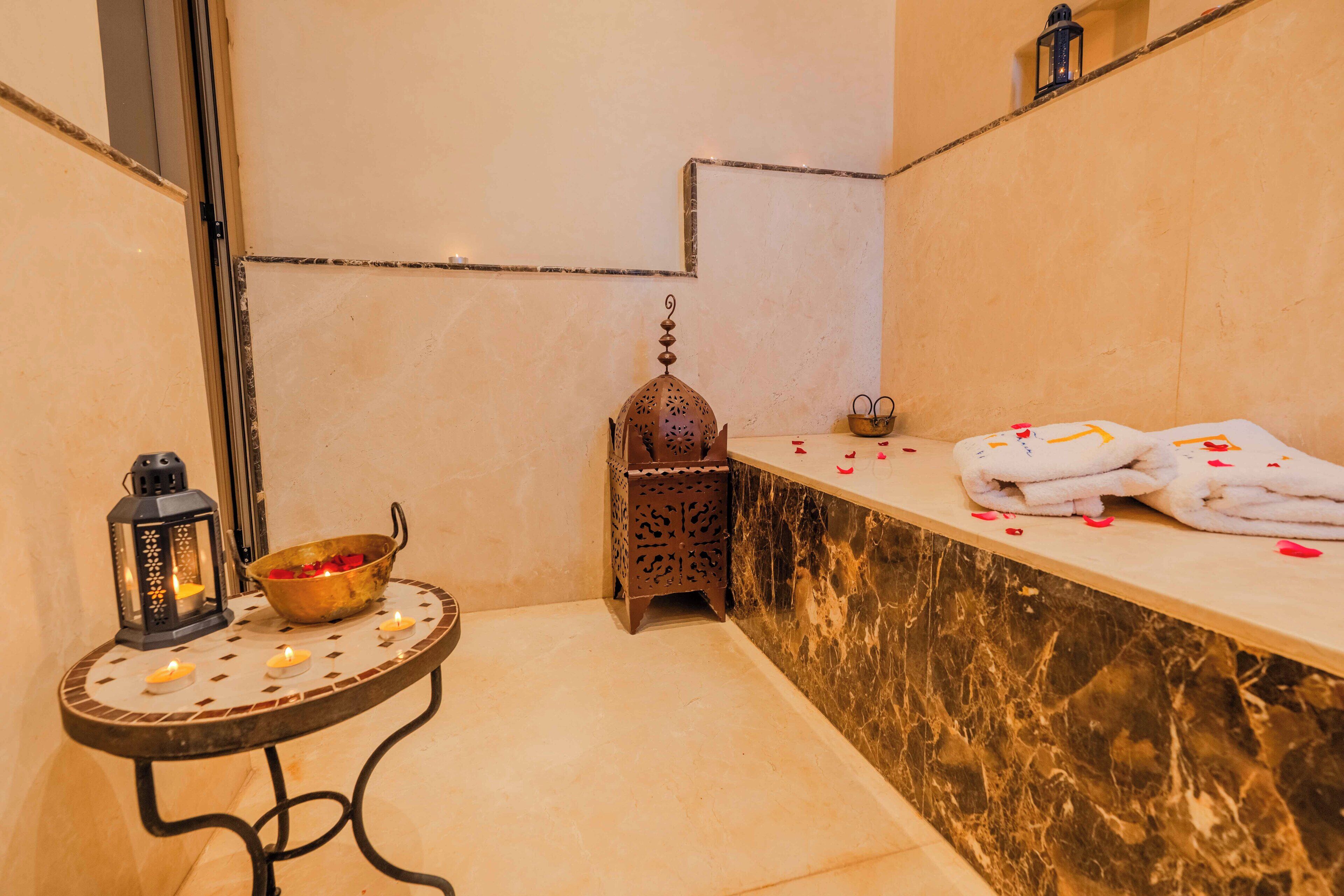 A bathroom with a marble countertop, a small table with candles, a decorative bowl, and a lantern.