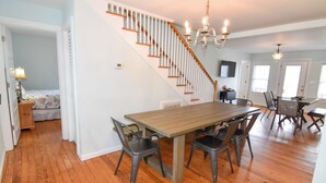 Ein geräumiger Essbereich mit Holztisch und -stühlen, eine Treppe mit Holzstufen und ein Chandelier.