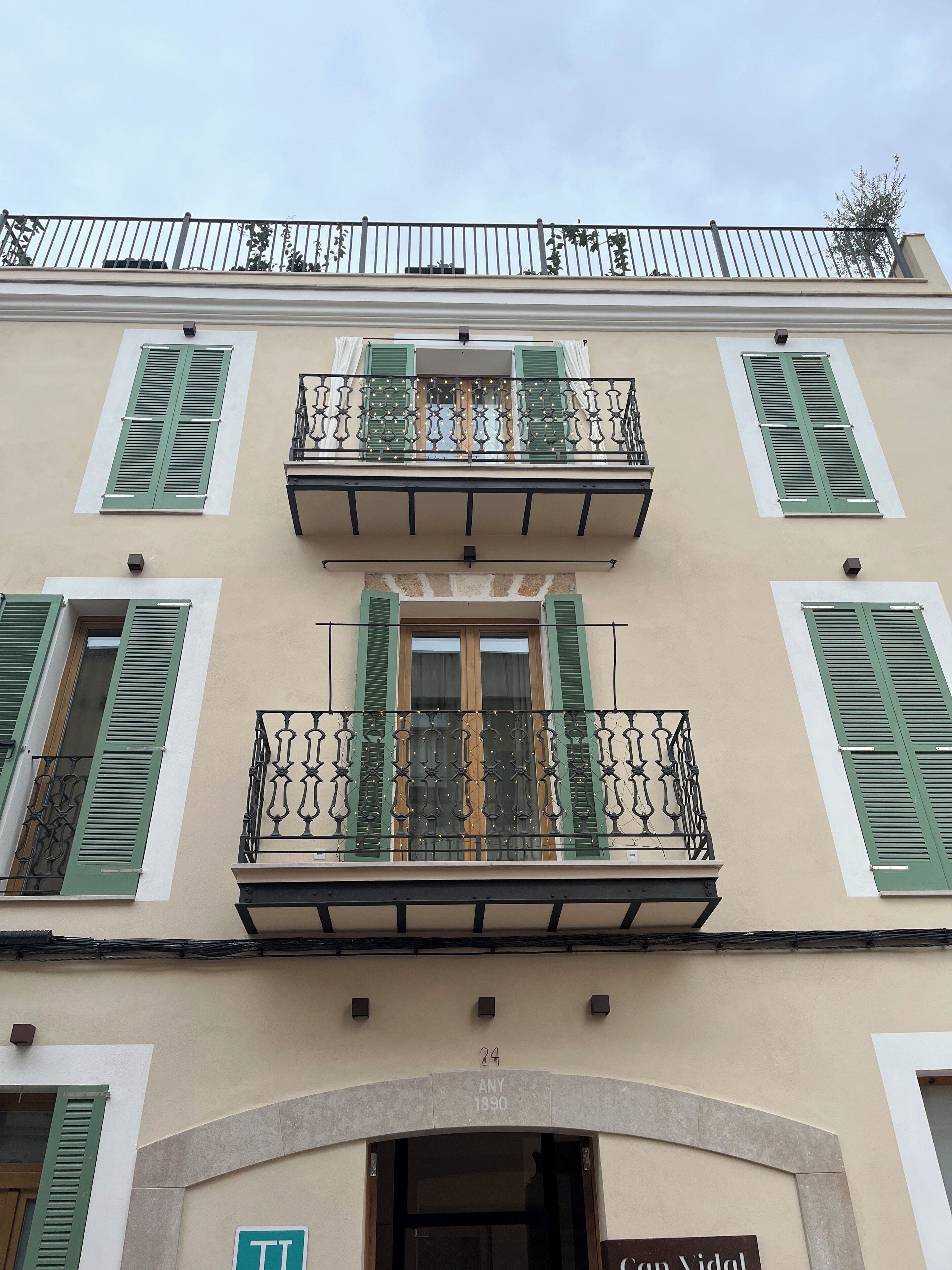 A building with a balcony, green shutters, and a sign indicating the address and year.