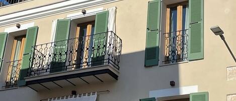 Un edificio con varios balcones, contraventanas verdes y un toldo blanco con el letrero 'Can Vidal'.