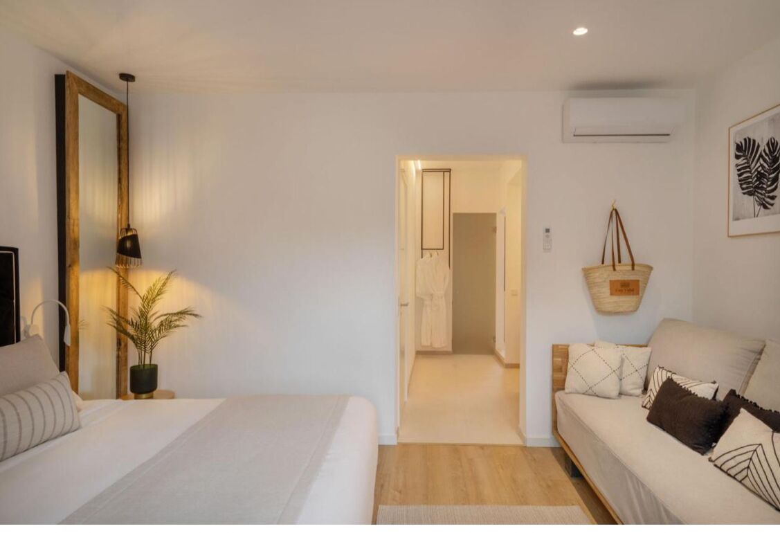 Une chambre d’hôtel avec un lit, un canapé, une suspension décorative et un miroir.