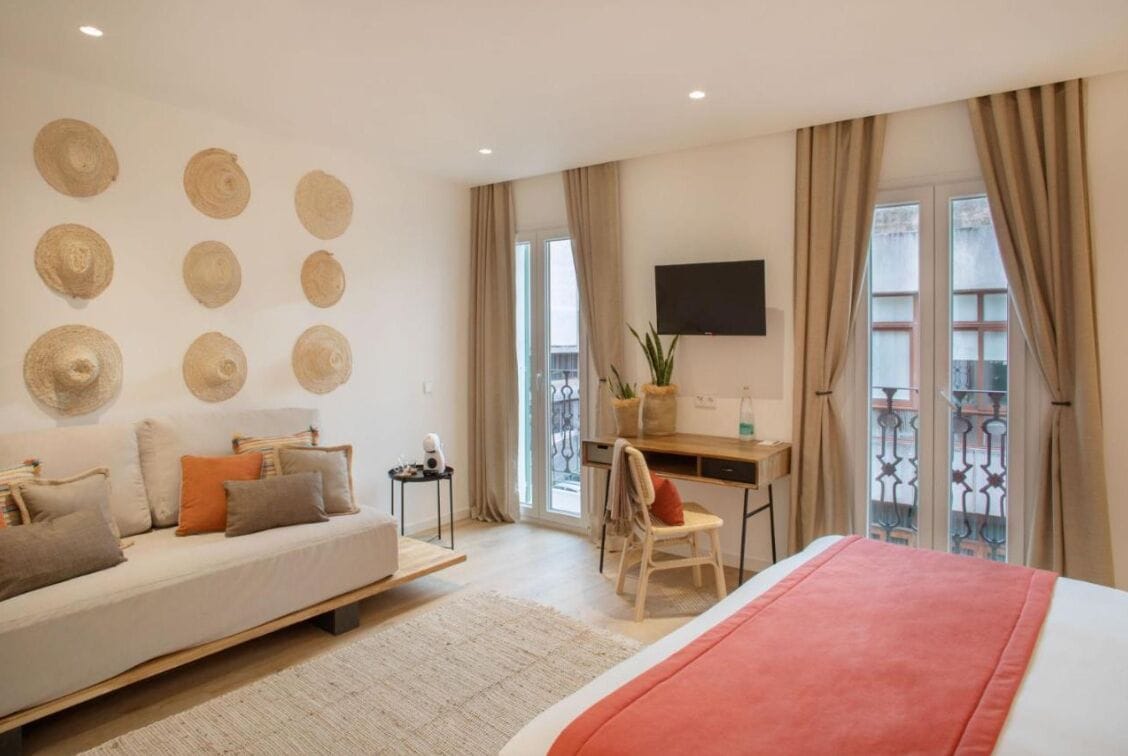 A modern bedroom with a bed, a desk, and a sofa.