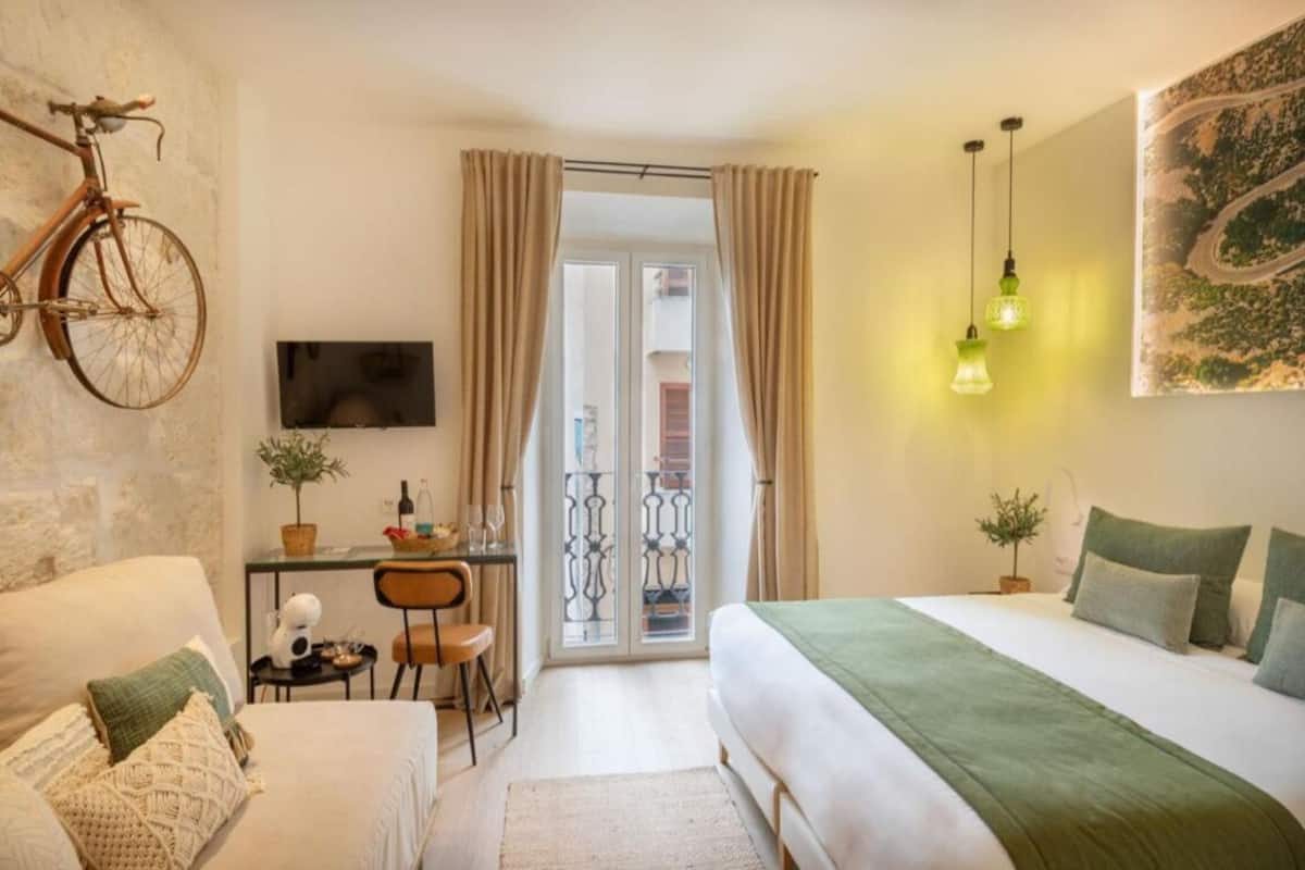 A cozy bedroom with a bed, a desk, and a bicycle.
