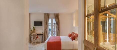 Una habitación de hotel con cama, escritorio y televisor.