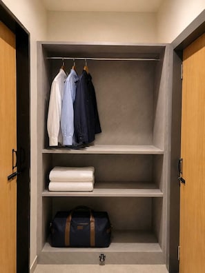 A wardrobe with hanging clothes and a folded towel on the shelves. - Hotel Abhishek Pride  (Shani Shingnapur)