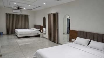 A hotel room with a large bed, a smaller bed, a ceiling fan, and a mirror.