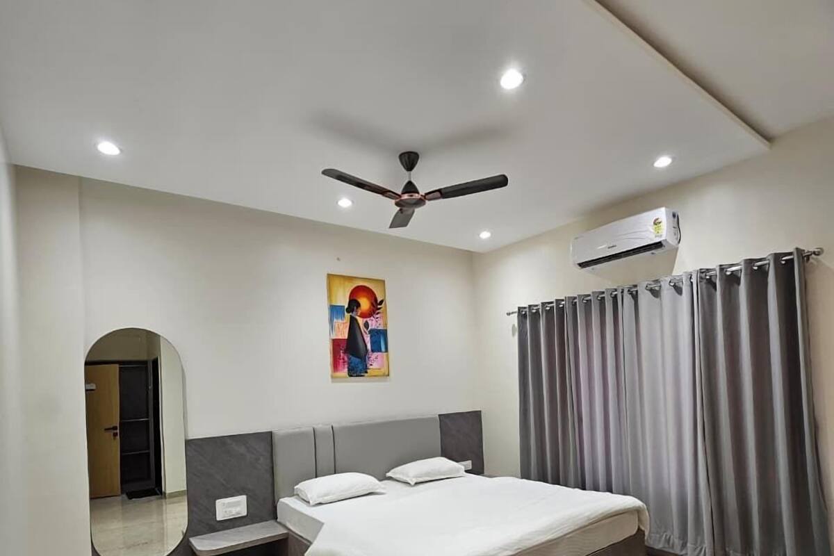Une chambre moderne avec un grand lit, un ventilateur de plafond, un climatiseur et un miroir.