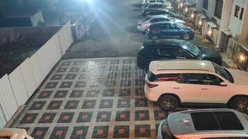 A parking lot with multiple cars parked in rows, a patterned floor, and buildings in the background.