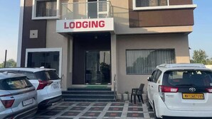A hotel named 'Hotel Abhishek Pride' with a 'Lodging' sign. There are two cars parked in front. - Hotel Abhishek Pride  (Shani Shingnapur)