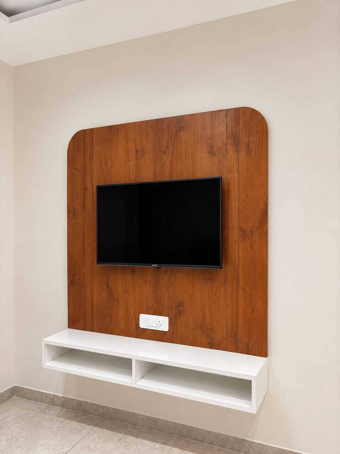 A flat-screen TV mounted on a wooden wall with a white shelf below.