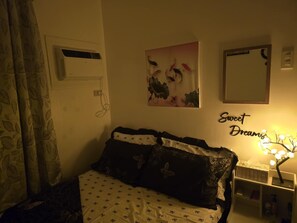 A bedroom with a bed, a nightstand, a wall-mounted mirror, and a floral artwork. - Comfort of Home in Panglao, Bohol.  Rest and enjoy our home while in the Island. (Dauis)