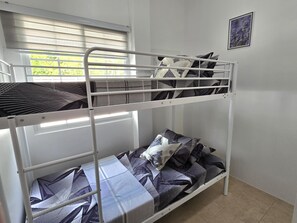 Een stapelbed met een raam, een foto aan de muur en een bedsprei met dessin.