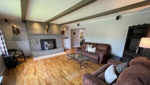 A living room with a stone fireplace, wooden flooring, and brown leather sofas.