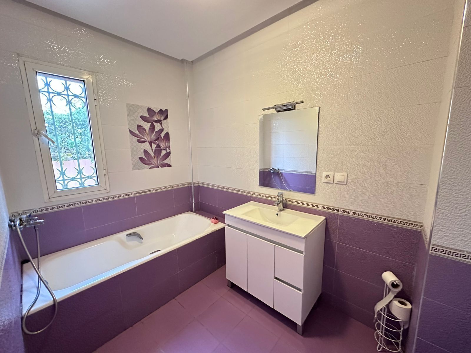 A bathroom with a bathtub, a sink, a mirror, and a toilet.