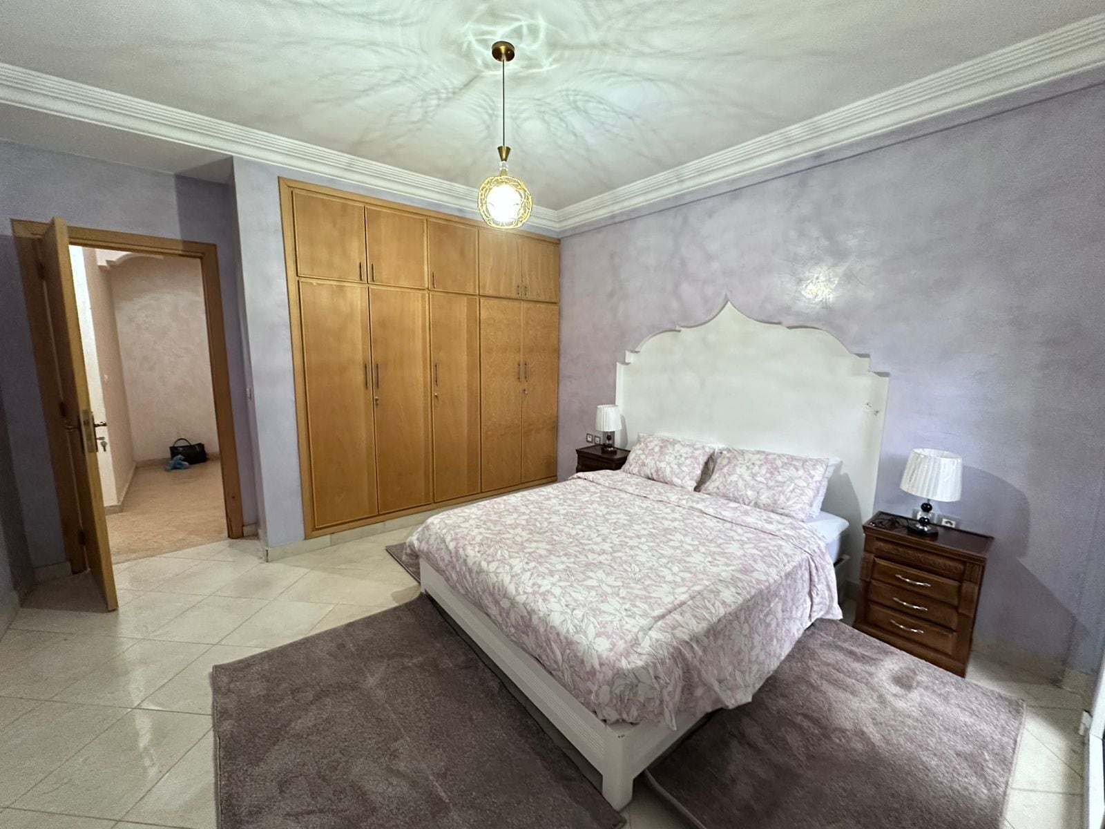 A bedroom with a bed, nightstands, a wardrobe, and a ceiling light.