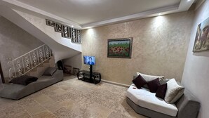 A living room with a sofa, a TV, and a painting on the wall. - residence riad zitoune (Marrakech)