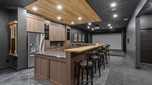 Een moderne keuken met een houten plafond, roestvrijstalen apparatuur en een bar met barkrukken.