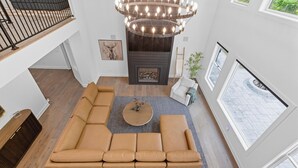 Een ruime woonkamer met een grote hoekbank, een ronde salontafel en een moderne kroonluchter.