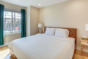 A hotel room with a large bed, a nightstand with a lamp, and a window with curtains. - Philly Hub Near University City, Lincoln Financial (Philadelphia)
