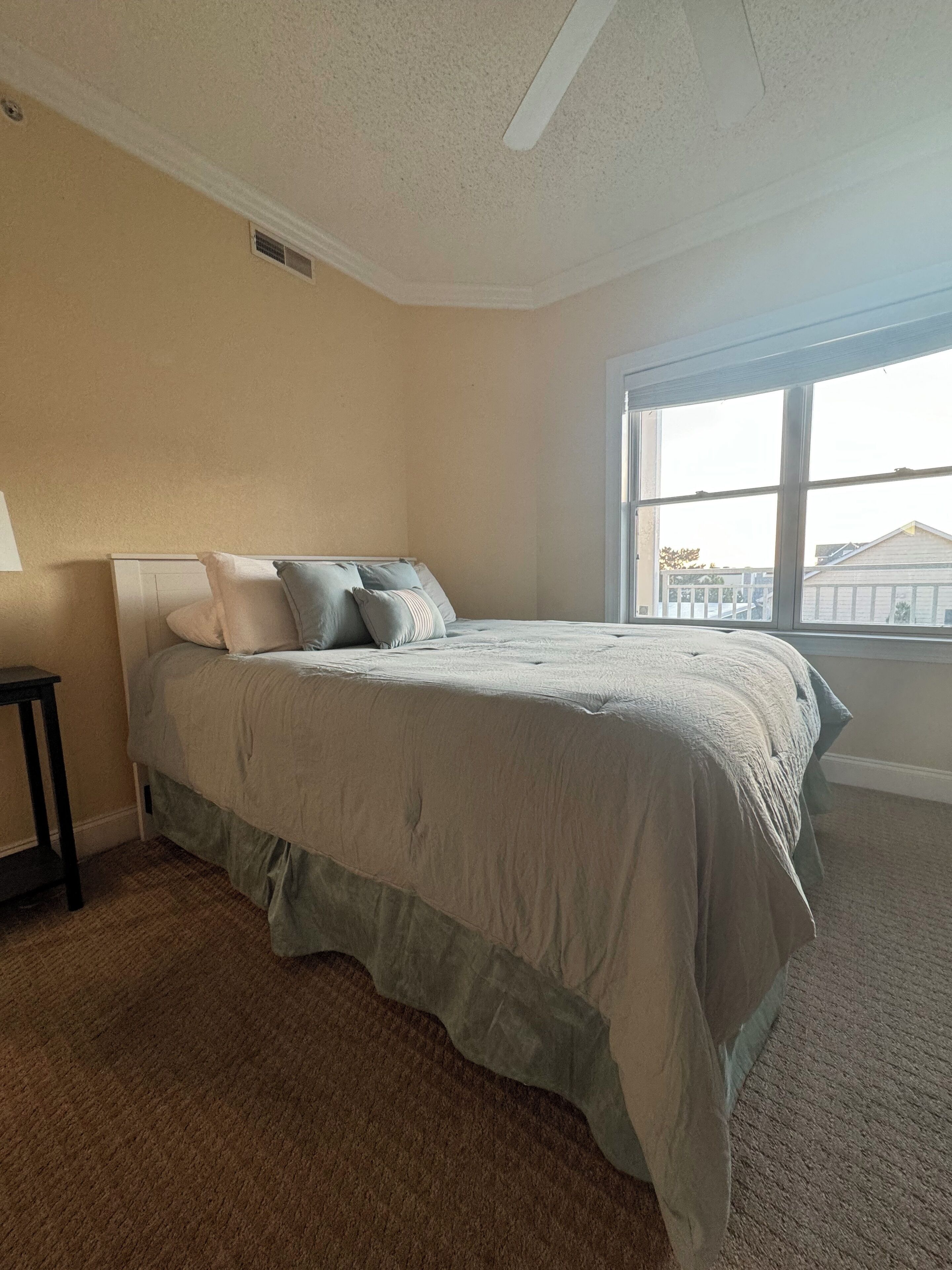 A bedroom with a bed, a window, and a small table.