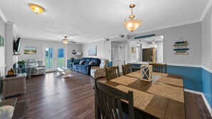 A spacious living area with a dining table, chairs, a sofa, and a ceiling fan. - Colony Club E1 (Gulf Shores)