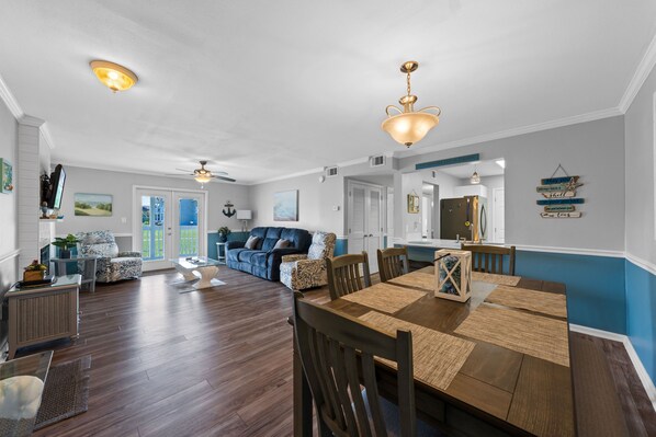 A spacious living area with a dining table, chairs, a sofa, and a ceiling fan.