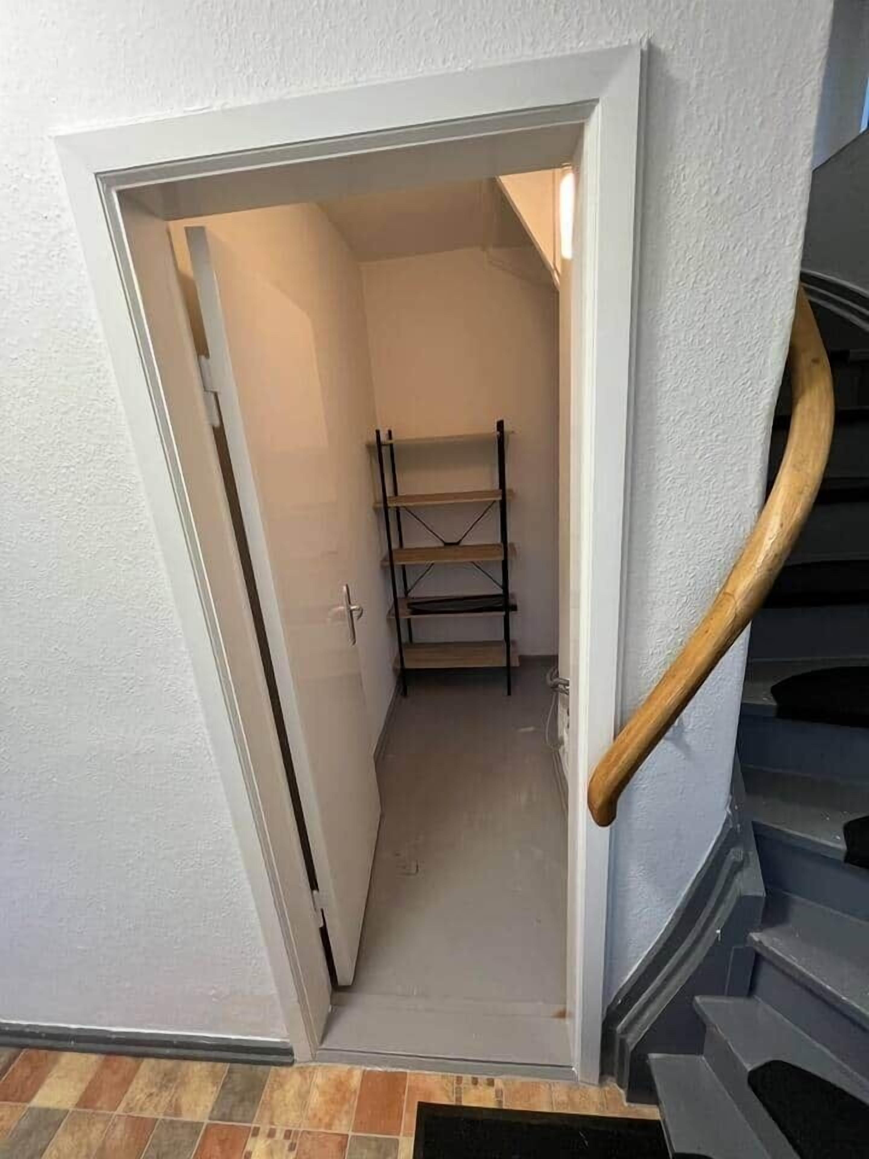 A narrow stairwell with a wooden handrail and a metal banister.