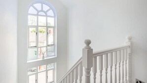 Un escalier blanc, doté d’une balustrade, mène à un palier.