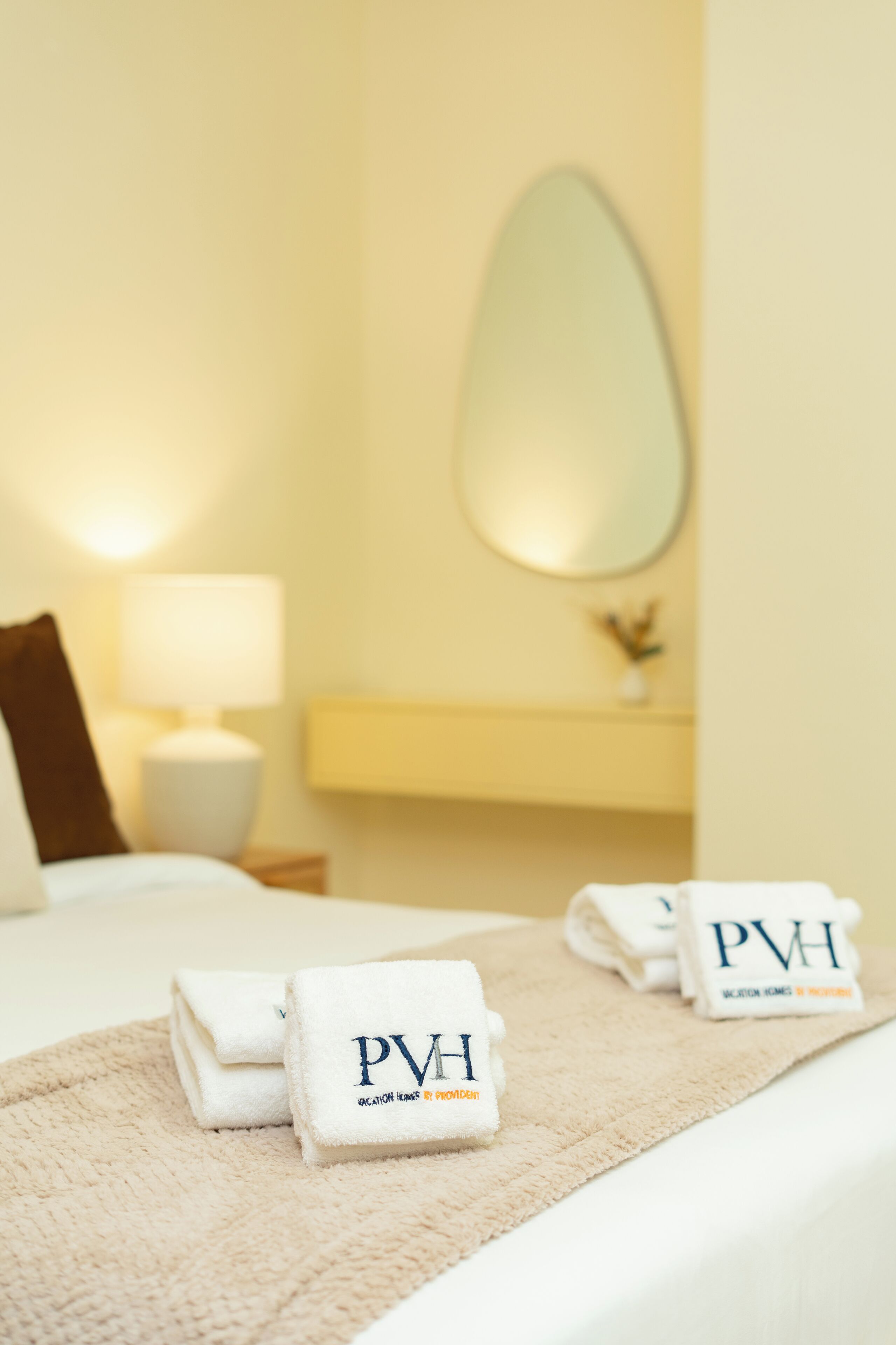 Un lit bien fait, avec des serviettes ornées du logo « PVH » et de l’inscription « WILTON HOMES & RESORTS ».