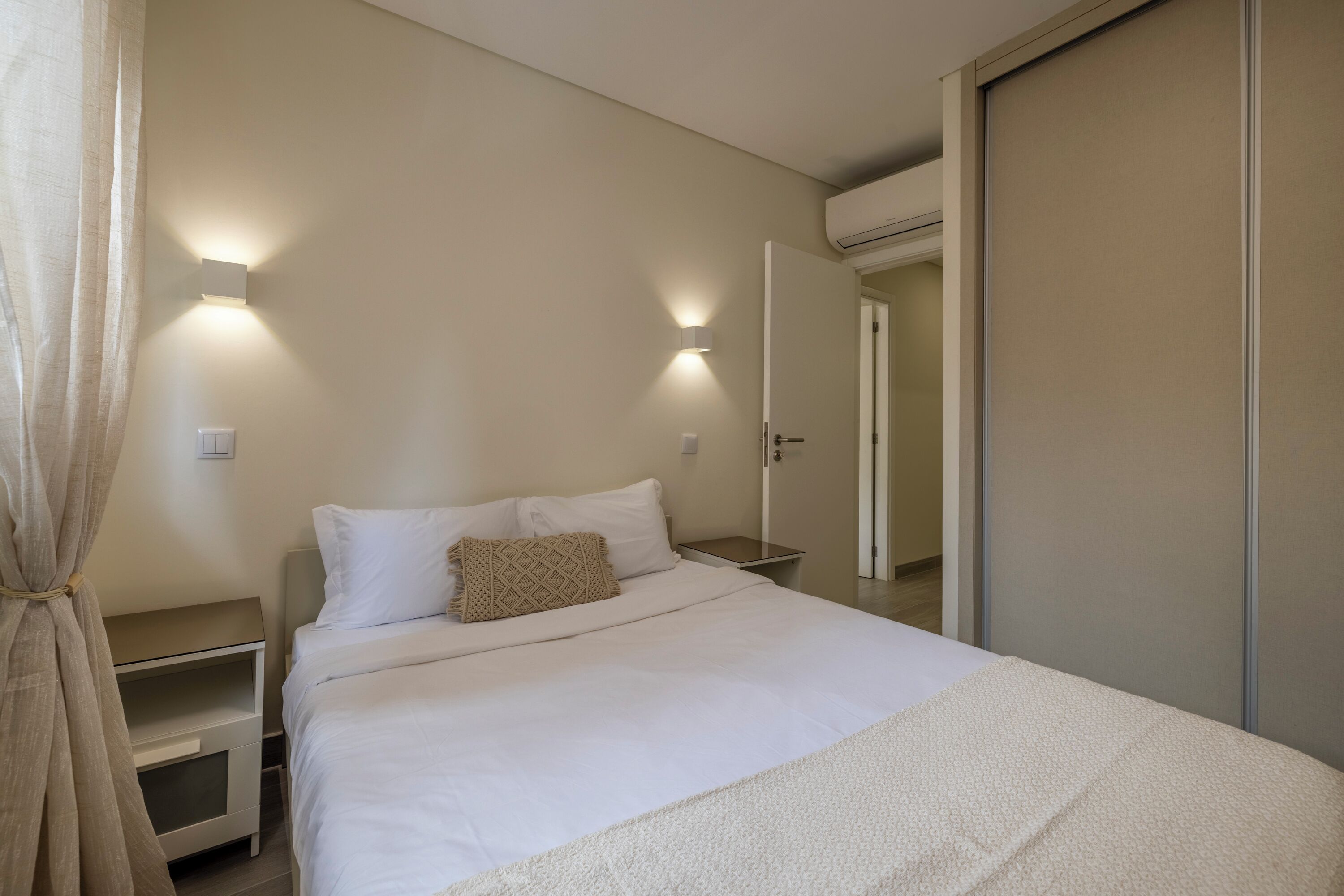 A bedroom with a bed, bedside tables, and a wardrobe.