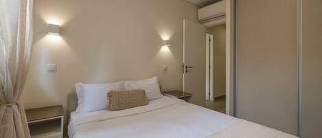 A bedroom with a bed, bedside tables, and a wardrobe.