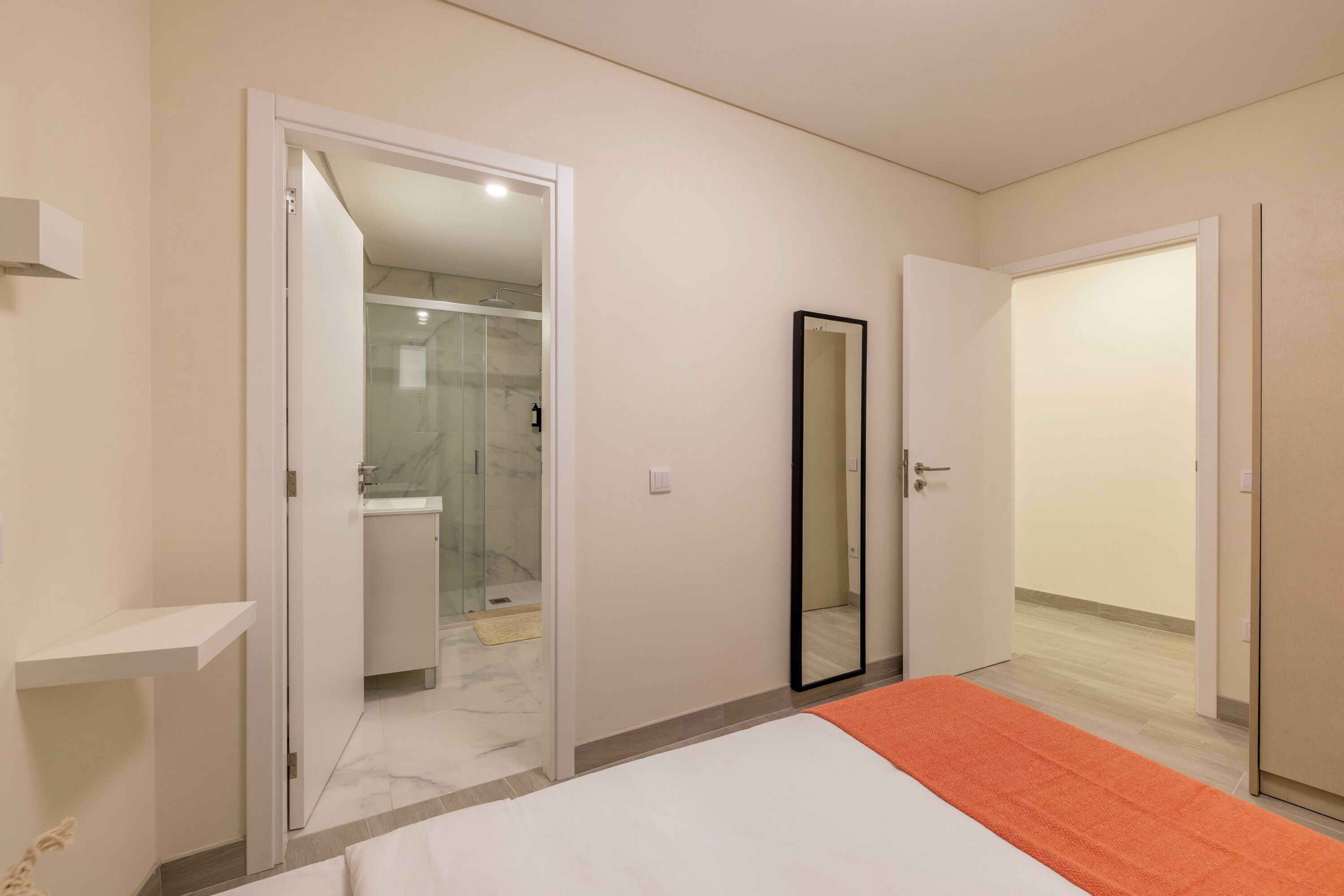 Ein Schlafzimmer mit Bett, ein Badezimmer mit Dusche und einem Spiegel.