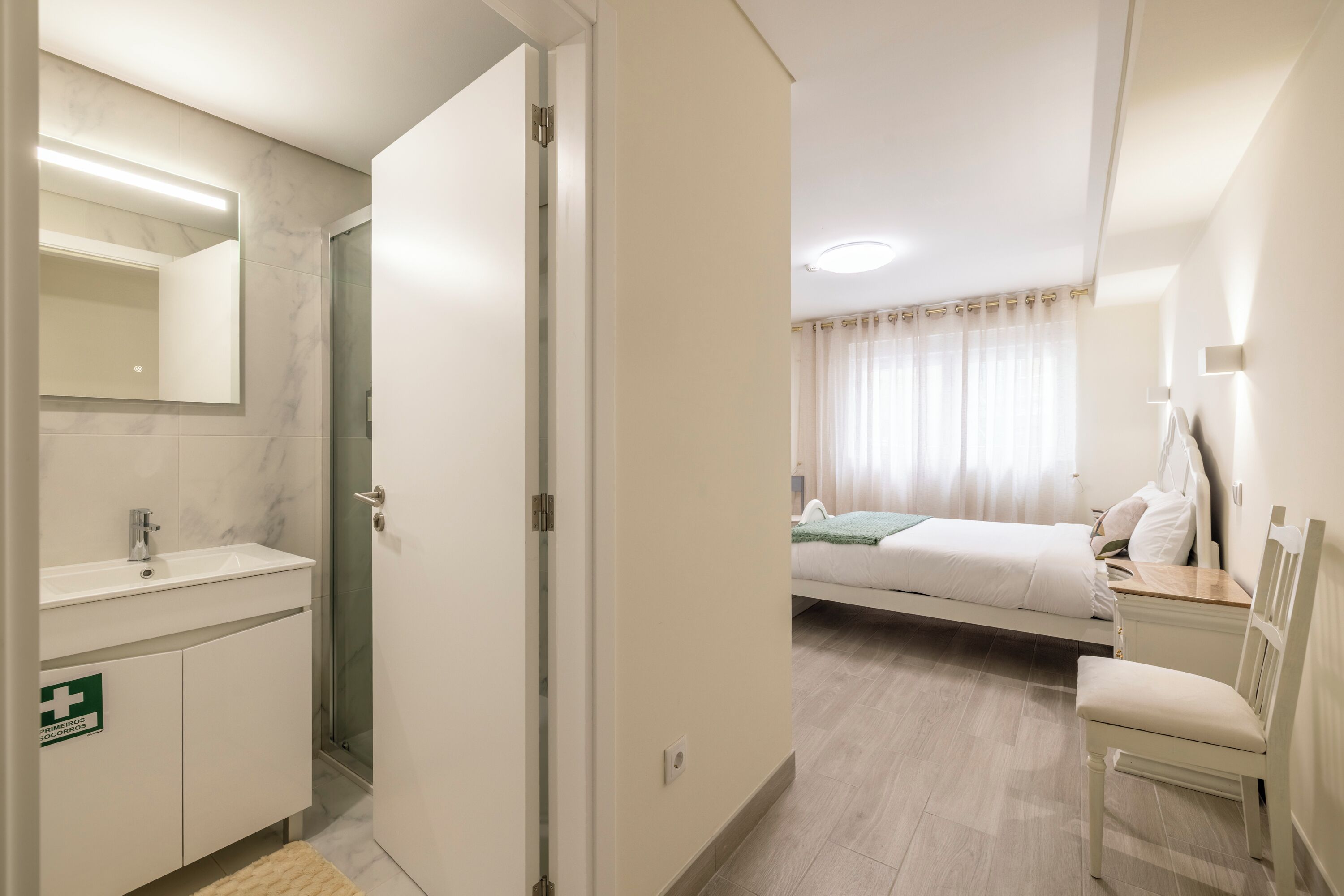 Een hotelkamer met een badkamer, een bed, een nachtkastje en een stoel.