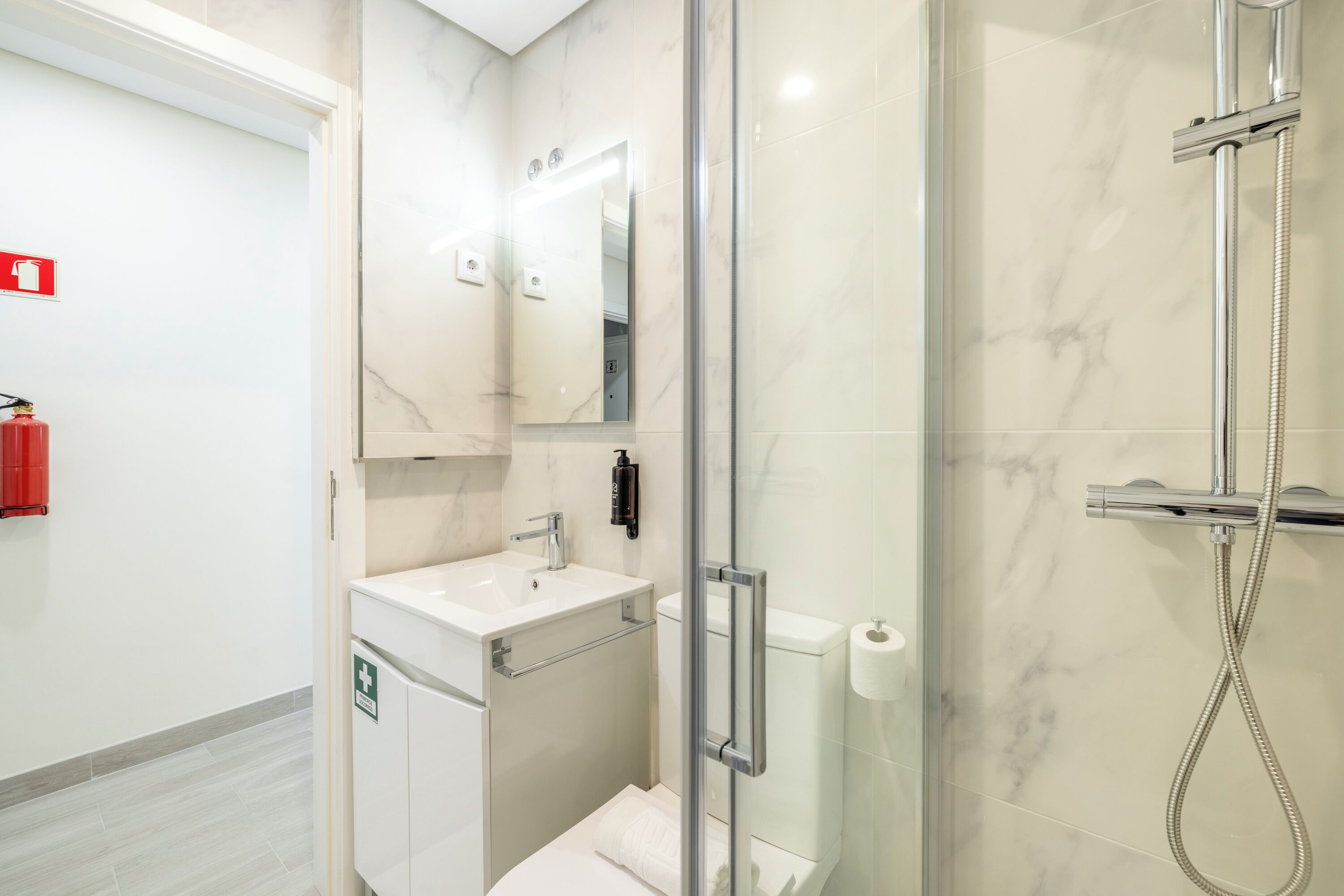 A modern bathroom with a glass-enclosed shower, a sink, and a toilet.